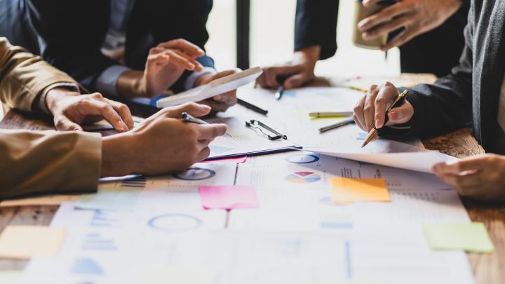 People sitting around a desk with papers and pens